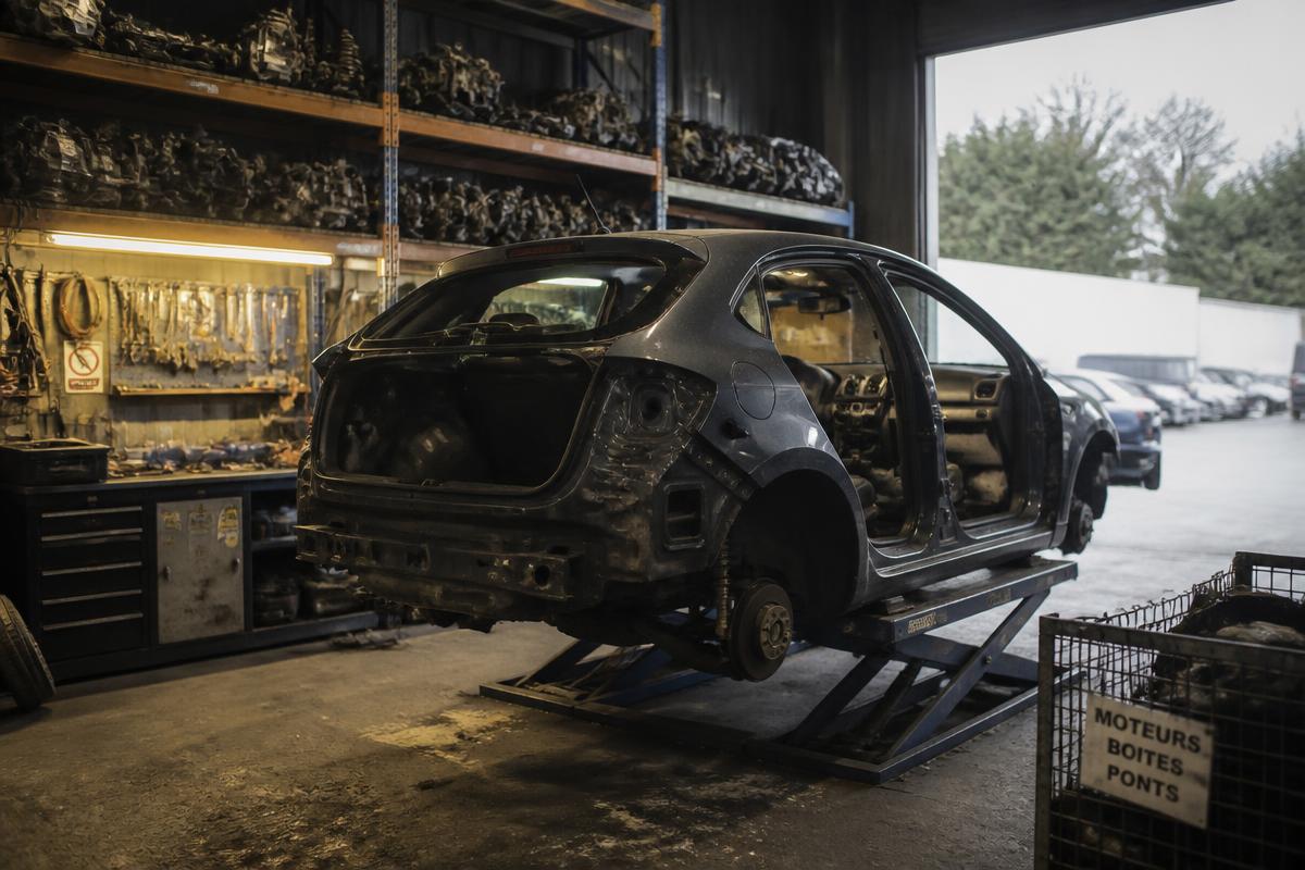 Partly stripped damaged hatchback on a lift in a dismantler workshop